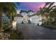 Beautiful two-story white home with a brick driveway and lush tropical landscaping at sunset at 3006 Christophers Watch Ln, Ruskin, FL 33570