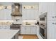 Modern kitchen with stainless steel appliances, white cabinets, and a stylish range hood above the stove at 3006 Christophers Watch Ln, Ruskin, FL 33570