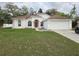 Charming single-story home with a two-car garage, lush green lawn, and a welcoming red front door at 3292 Dow Ln, Spring Hill, FL 34609