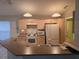 Functional kitchen featuring wooden cabinetry, white appliances, and a breakfast bar at 3292 Dow Ln, Spring Hill, FL 34609