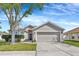 Charming single-story home with a two-car garage, well-manicured lawn, and mature shade tree in the front yard at 3412 Trapnell Ridge Dr, Plant City, FL 33567