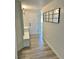 Inviting hallway with modern gray vinyl plank flooring, coat hooks and a grid pattern mirror at 3455 Overland Dr, Holiday, FL 34691
