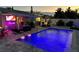 Night view of an outdoor pool with neon sign, poolside lounge area, and flamingo pool floats at 427 79Th Ave, St Pete Beach, FL 33706