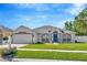 Charming single-story home featuring a manicured lawn, blue front door, and two-car garage at 703 June Lake Ln, Brandon, FL 33510