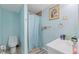 Cozy bathroom with toilet, vanity with toiletries, shower with blue curtain, and decorative artwork at 7143 Sealawn Dr, Spring Hill, FL 34606
