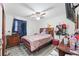 This bedroom features a ceiling fan, hard flooring, and bright colors, with decor and a red coverlet on the bed at 7143 Sealawn Dr, Spring Hill, FL 34606