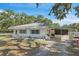 Charming exterior view featuring white exterior, decorative shutters, tidy landscaping, and covered carport at 7143 Sealawn Dr, Spring Hill, FL 34606