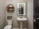 Bathroom featuring a modern pedestal sink, LED mirror and decorative shelving with reading material at 8766 Capstone Ranch Dr, New Port Richey, FL 34655