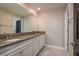 Bathroom with double granite sinks, white cabinetry, tile flooring, and a black door at 8766 Capstone Ranch Dr, New Port Richey, FL 34655