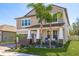 Attractive two-story house with a brick driveway, palm trees, and welcoming front porch at 8766 Capstone Ranch Dr, New Port Richey, FL 34655