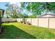 View of the backyard with garden beds, a well-manicured lawn, and a tall white fence for privacy at 17113 Sunshine Mimosa St, Wimauma, FL 33598