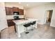Modern kitchen featuring dark wood cabinets, white backsplash, an island, and stainless steel appliances at 17113 Sunshine Mimosa St, Wimauma, FL 33598