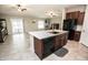 Open kitchen with an island, dark cabinets, stainless steel appliances, and a seamless flow to the living area at 17113 Sunshine Mimosa St, Wimauma, FL 33598