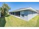 Back exterior showcasing the enclosed back porch and large, grassy backyard at 10216 Moshie Ln, San Antonio, FL 33576