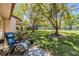 Backyard view with comfortable seating, lush lawn, mature trees, and a glimpse of the tennis court at 1159 Montrose Pl, Dunedin, FL 34698