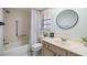 Well-lit bathroom featuring a shower over tub, a vanity with a sink, and a decorative mirror at 1159 Montrose Pl, Dunedin, FL 34698