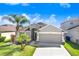 Single-story home boasts a neat lawn, mature palm trees, and a convenient two-car garage at 15414 Fire Rock Pl, Ruskin, FL 33573