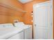 Laundry room with washer, dryer, shelving, and bright orange walls at 15414 Fire Rock Pl, Ruskin, FL 33573