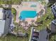An aerial view of a community pool surrounded by brick pavers, lounge chairs, palm trees, and parking spots at 1600 Gulf Blvd # 817, Clearwater Beach, FL 33767