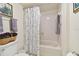 Cozy bathroom featuring a tiled shower with a floral curtain and violet accent flowers at 1600 Gulf Blvd # 817, Clearwater Beach, FL 33767