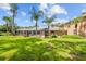 Expansive backyard featuring a screened-in pool, lush lawn, and mature palm trees, perfect for outdoor living and relaxation at 16211 Villarreal De Avila, Tampa, FL 33613