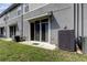 View of the gray townhome backyard with sliding glass door, air conditioner and grassy area at 2039 Strathmill Dr, Clearwater, FL 33755