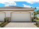 Exterior of home displaying two-car garage with paver driveway and minimal landscaping at 20411 Symphony Pl, Venice, FL 34293