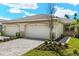 Home exterior displaying a two-car garage, a paver driveway, and landscaping in front of the home under a cloudy blue sky at 20411 Symphony Pl, Venice, FL 34293