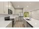 Bright kitchen with stainless steel appliances, white cabinets, quartz counters, and sliding glass doors to the backyard at 20411 Symphony Pl, Venice, FL 34293