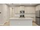 Modern kitchen featuring white cabinets, stainless steel appliances, a center island, and wood-look flooring at 20411 Symphony Pl, Venice, FL 34293