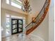 Bright foyer with grand staircase, chandelier, and marble flooring at 2053 N Pointe Alexis Dr, Tarpon Springs, FL 34689