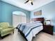 This bedroom features an arched window, light wood floors, and blue walls at 2204 Margaret Way, Dunedin, FL 34698