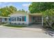 Exterior view of a home with blue shutters, manicured lawn, and a covered carport at 238 Pelican N Dr, Oldsmar, FL 34677