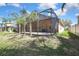 View of the backyard featuring a spacious screened-in patio, green lawn, and tropical trees at 3033 Marble Crest Dr, Land O Lakes, FL 34638