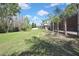 Expansive green backyard featuring mature trees, a white fence line, and a screened patio at 3033 Marble Crest Dr, Land O Lakes, FL 34638