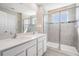 Modern bathroom featuring a double vanity, glass-enclosed shower, and neutral tile at 30903 Quail Caper Cir, San Antonio, FL 33576