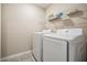 Bright laundry room features a modern white washer and dryer set with a wire storage shelf above at 30903 Quail Caper Cir, San Antonio, FL 33576