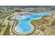 An aerial view of a community lagoon with beach, pool, floating obstacle course, lounge chairs, and amenities building at 31616 Parkland Bay Way, San Antonio, FL 33576