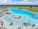 Aerial view features a pristine lagoon with water slides, an inflatable park, and a sandy beach at 31616 Parkland Bay Way, San Antonio, FL 33576