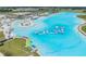 An aerial view showcases the large lagoon, the sandy beach, and an inflatable water park at 31616 Parkland Bay Way, San Antonio, FL 33576