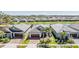 An aerial view shows a neighborhood, lake, and the home featuring a well-manicured lawn and landscaping at 31616 Parkland Bay Way, San Antonio, FL 33576