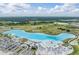 This aerial view shows a lagoon surrounded by green fields, a parking lot, and community amenity buildings at 31616 Parkland Bay Way, San Antonio, FL 33576