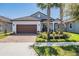 Charming one-story home featuring a brick driveway and a beautifully landscaped front yard with palm trees at 31616 Parkland Bay Way, San Antonio, FL 33576