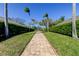 Paver walkway lined by manicured hedges and palm trees leading to well-maintained homes at 4702 Corsage Dr, Lutz, FL 33558