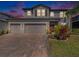 Charming two-story home with a three-car garage, brick paver driveway, and lush landscaping at 4923 Eagle Rock Dr, Wimauma, FL 33598