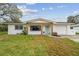 Charming single-story home featuring a manicured lawn and a welcoming blue front door, complemented by wood support beams at 7310 Donna Dr, New Port Richey, FL 34652