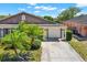 Charming home exterior featuring a two-car garage, lush landscaping, and a well-maintained driveway at 8551 N Hyaleah Rd, Tampa, FL 33617