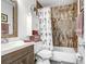 Bright bathroom with floral shower curtain, ample cabinet storage, and decorative mirror at 113 Seahorse Se Dr # D, St Petersburg, FL 33705