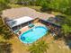 Aerial view of backyard pool with a deck, screened porch, an outdoor kitchen, and mature landscaping at 11434 Minnieola Dr, New Port Richey, FL 34654