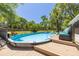 Backyard view of an above ground pool surrounded by a wooden deck and lush greenery at 11434 Minnieola Dr, New Port Richey, FL 34654